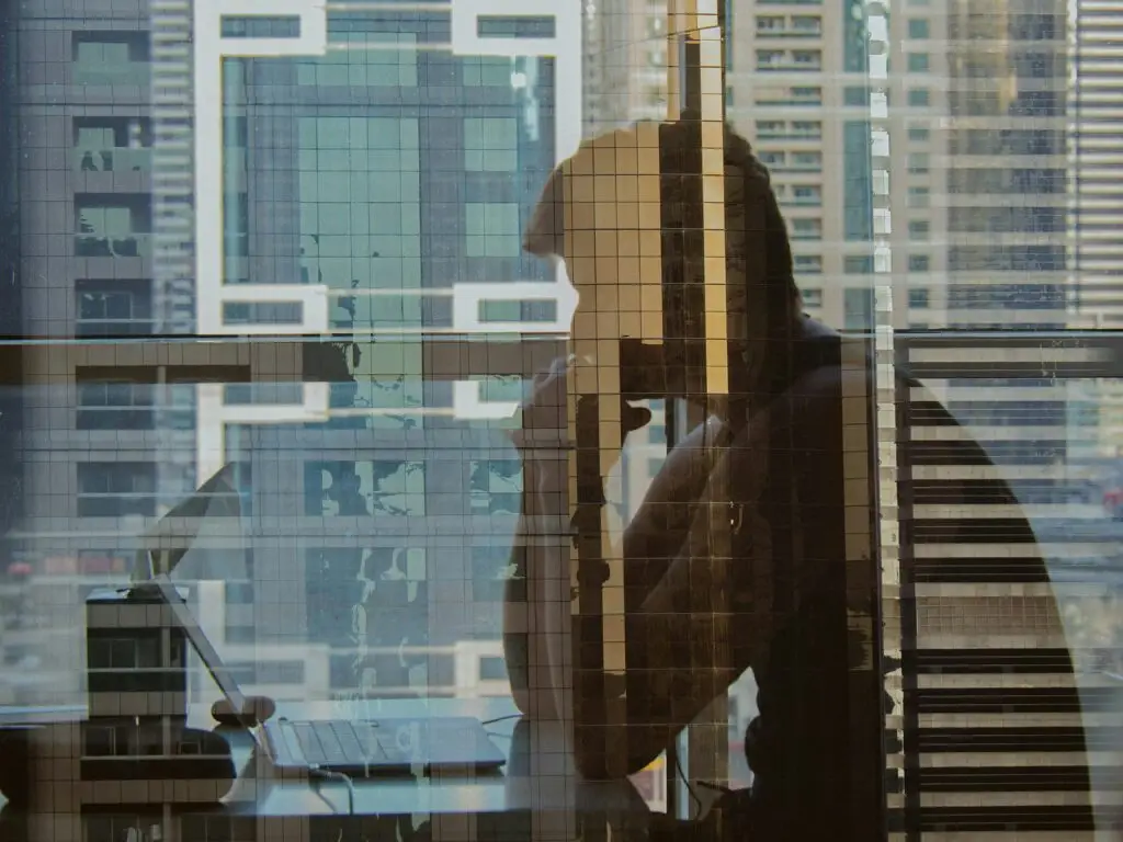 Professional standing by an office window reflecting on career choices and income optionality.